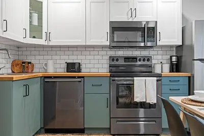 a kitchen with stainless steel appliances and white cabinets at Elegant Boho Retreat - 8 min to WEM in Edmonton
