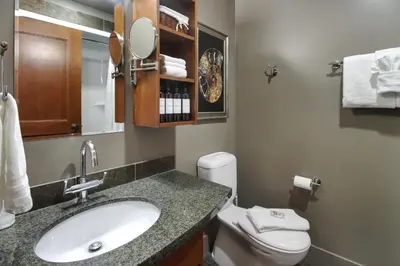a bathroom with a sink and a toilet and a mirror at Marvellous Mountain Condo- Pets - Pool & Hot Tub managed by Little Sister Getaways in Canmore