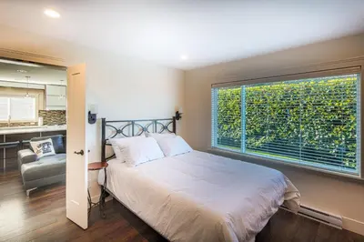a bedroom with a bed and a large window at Qualicum Beach Ocean Suites in Qualicum Beach
