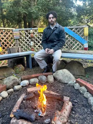 a man sitting on a bench next to a fire at Gabriola Island B&B By The Sea in Gabriola
