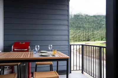 a table and chairs on a balcony with a window at Summit Views Condo by Revelstoke Vacations in Revelstoke