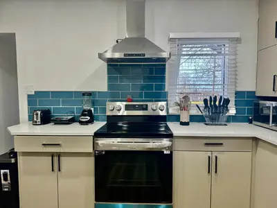 a kitchen with a black stove and blue tiles at Farmstay in Edmonton in Duffield