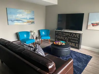 a living room with a leather couch and blue chairs at White Rock Beach getaway in White Rock