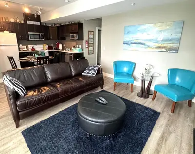 a living room with a leather couch and blue chairs at White Rock Beach getaway in White Rock