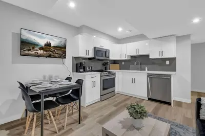 a kitchen with white cabinets and a table with chairs at ModernSuite*NearAirport*2Queens*2Bedroom*FullKitchen in Edmonton