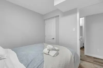 a white bedroom with a bed with towels on it at ModernSuite*NearAirport*2Queens*2Bedroom*FullKitchen in Edmonton