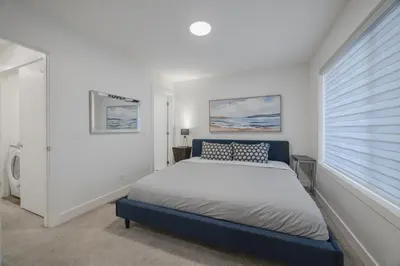 a white bedroom with a bed and a window at Townhome with Free Parking, Near Downtown in Calgary