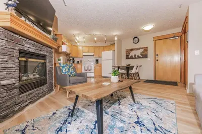 a living room with a table and a fireplace at Lovely Mountain View 2 Bedroom Suite in Canmore