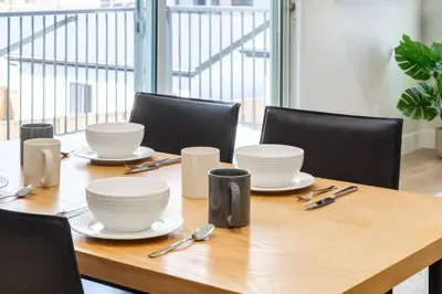 a wooden table with plates and utensils on it at Pet Friendly & Accessible, 4 Beds in Calgary