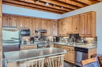 a kitchen with wooden cabinets and stainless steel appliances at Snowy Creek by Okanagan Premier in Big White