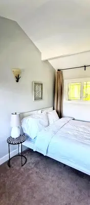 a bedroom with a large white bed and a table at White House Tofino Downtown Villa in Tofino