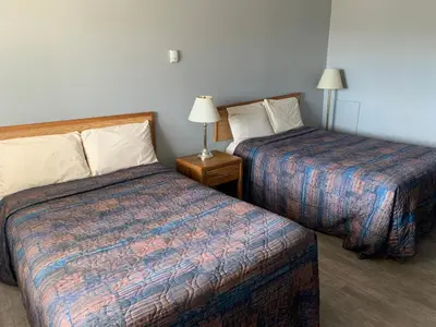 a hotel room with two beds and two lamps at Wild Rose Inn in Vegreville
