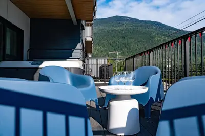 a balcony with blue chairs and a table with wine glasses at Tucker's Place in Revelstoke