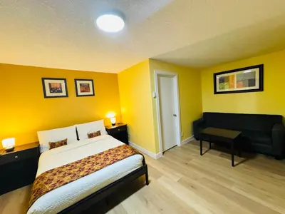 a yellow room with a bed and a couch at Avola Mountain Lodge in Avola