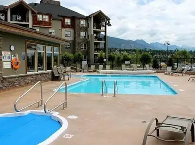 a pool at a resort with chairs and a building at Contemporary, Cozy, Pool, Hot Tub, Lake Front in Invermere