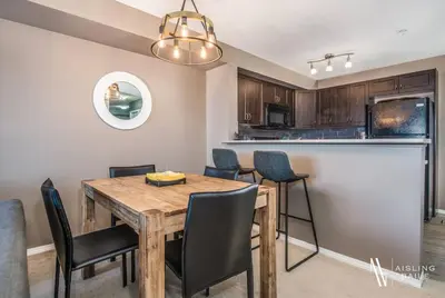 a kitchen and dining room with a wooden table and chairs at Contemporary, Cozy, Pool, Hot Tub, Lake Front in Invermere