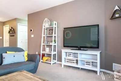 a living room with a flat screen tv on a white stand at Contemporary, Cozy, Pool, Hot Tub, Lake Front in Invermere