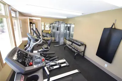 a gym with several treadmills and machines in a room at Contemporary, Cozy, Pool, Hot Tub, Lake Front in Invermere