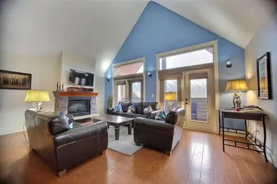 a living room with leather furniture and a blue ceiling at Magnificent Mountain Penthouse - Hot Tub & Pool managed by Little Sister Getaways in Canmore