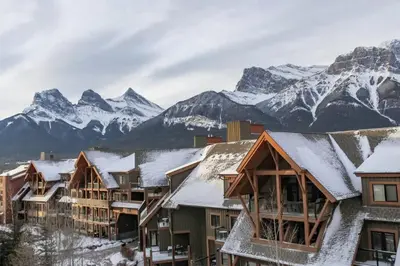 a resort with snow covered mountains in the background at Magnificent Mountain Penthouse - Hot Tub & Pool managed by Little Sister Getaways in Canmore