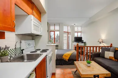 a kitchen with a sink and a living room at Studio in Alpenglow Lodge, Private Balcony with Mountain Views, Gym, Epic Location in Whistler