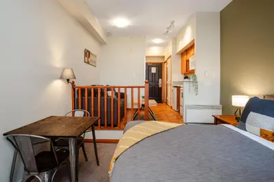 a bedroom with a bed and a table and a staircase at Studio in Alpenglow Lodge, Private Balcony with Mountain Views, Gym, Epic Location in Whistler