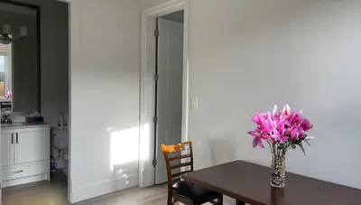 a vase of pink flowers on a table in a kitchen at Home In Vancouver in Richmond