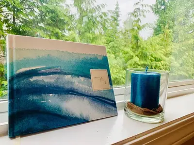 a candle sitting on a window sill next to a painting at Blue Cedar Suite in Tofino