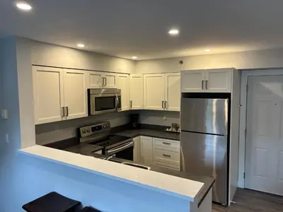 a kitchen with white cabinets and a stainless steel refrigerator at Gibsons Landing Inn in Gibsons