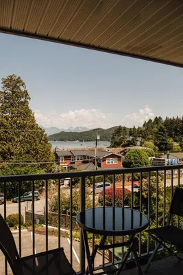 a patio with a table and chairs on a balcony at Gibsons Landing Inn in Gibsons