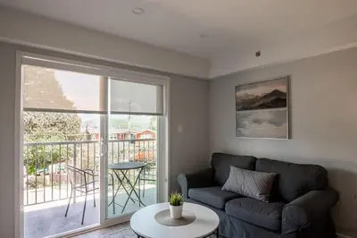 a living room with a couch and a balcony at Gibsons Landing Inn in Gibsons