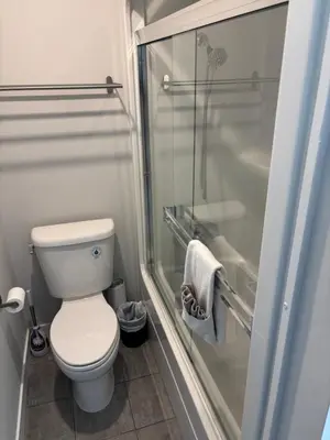 a bathroom with a toilet and a glass shower at Gibsons Landing Inn in Gibsons