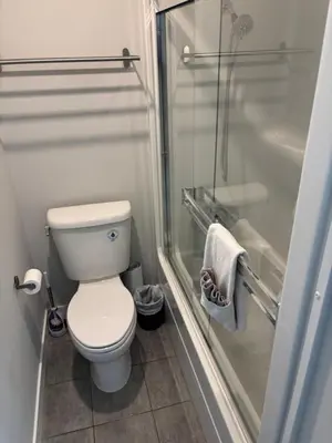 a small bathroom with a toilet and a shower at Gibsons Landing Inn in Gibsons