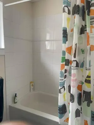 a bathroom with a tub and a shower curtain at Marine Drive Station Entire House in Vancouver