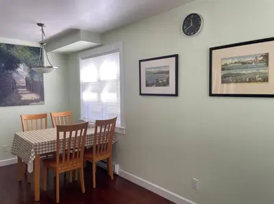 a dining room with a table and chairs and a clock at Marine Drive Station Entire House in Vancouver