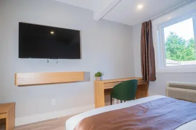 a bedroom with a bed and a desk and a tv at InnTowne Motel II in Hope