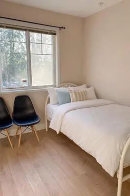 a bedroom with a bed and two chairs and a window at 3 Bedrooms 1 Bath in SHARE HOUSE at Coquitlam Central Mall & skytrain in Port Coquitlam