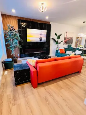 a living room with an orange couch and a flat screen tv at M21 Luxurious, Downtown River Valley Home, Centrally located, Close to everything in Edmonton