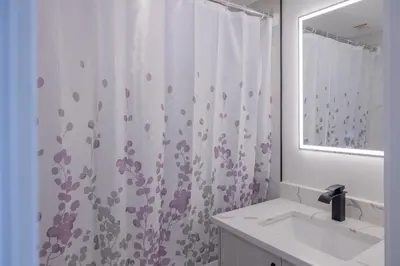 a bathroom with a shower curtain and a sink at Premium Deluxe suites 201 in Peachland
