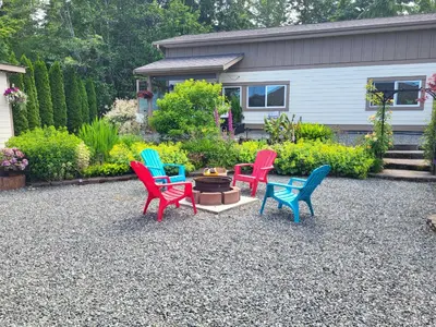 four colorful chairs sitting around a fire pit in a yard at The White Rabbit Inn in Courtenay