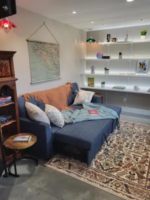 a living room with a blue couch and shelves at The White Rabbit Inn in Courtenay