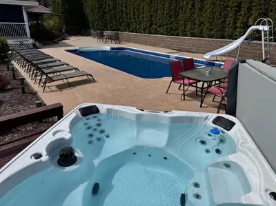 a hot tub in front of a swimming pool at heated pool, hot tub, 3 AC ensuites, lake view in West Kelowna