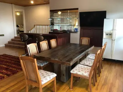 a kitchen with a wooden table with chairs and a refrigerator at heated pool, hot tub, 3 AC ensuites, lake view in West Kelowna
