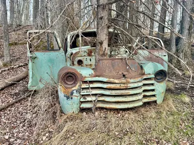 an old rusted out truck sitting in the woods at DreamLand Farms, Edmonton in Duffield