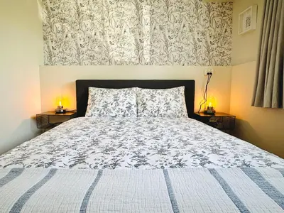 a bedroom with a bed with a white and blue comforter at 2BR 1BA Garden View Guest Suite - King-size Bed - Free Parking in Vancouver