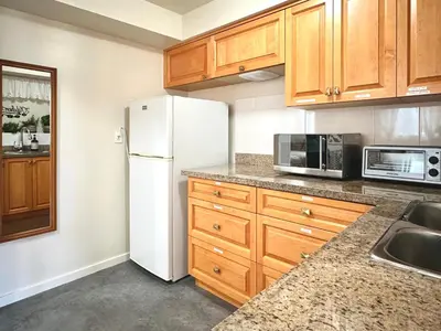 a kitchen with a white refrigerator and wooden cabinets at 2BR 1BA Garden View Guest Suite - King-size Bed - Free Parking in Vancouver