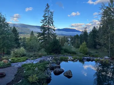 a pond with rocks and trees and mountains in the background at beard's creek bed and breakfast in Parson