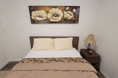 a bedroom with a bed with a painting on the wall at Brand New Suite in the Lakes in Calgary