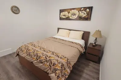 a bedroom with a bed and a table with a lamp at Brand New Suite in the Lakes in Calgary