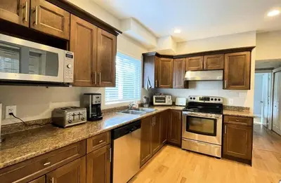 a kitchen with wooden cabinets and stainless steel appliances at King and Queen rooms -J&J Chilliwack in Chilliwack
